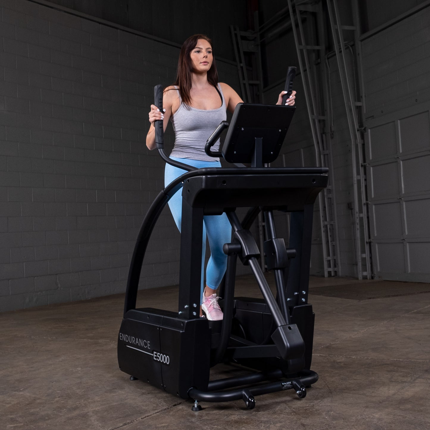User exercising on the E5000 elliptical trainer demonstrating natural stride and upper body handles