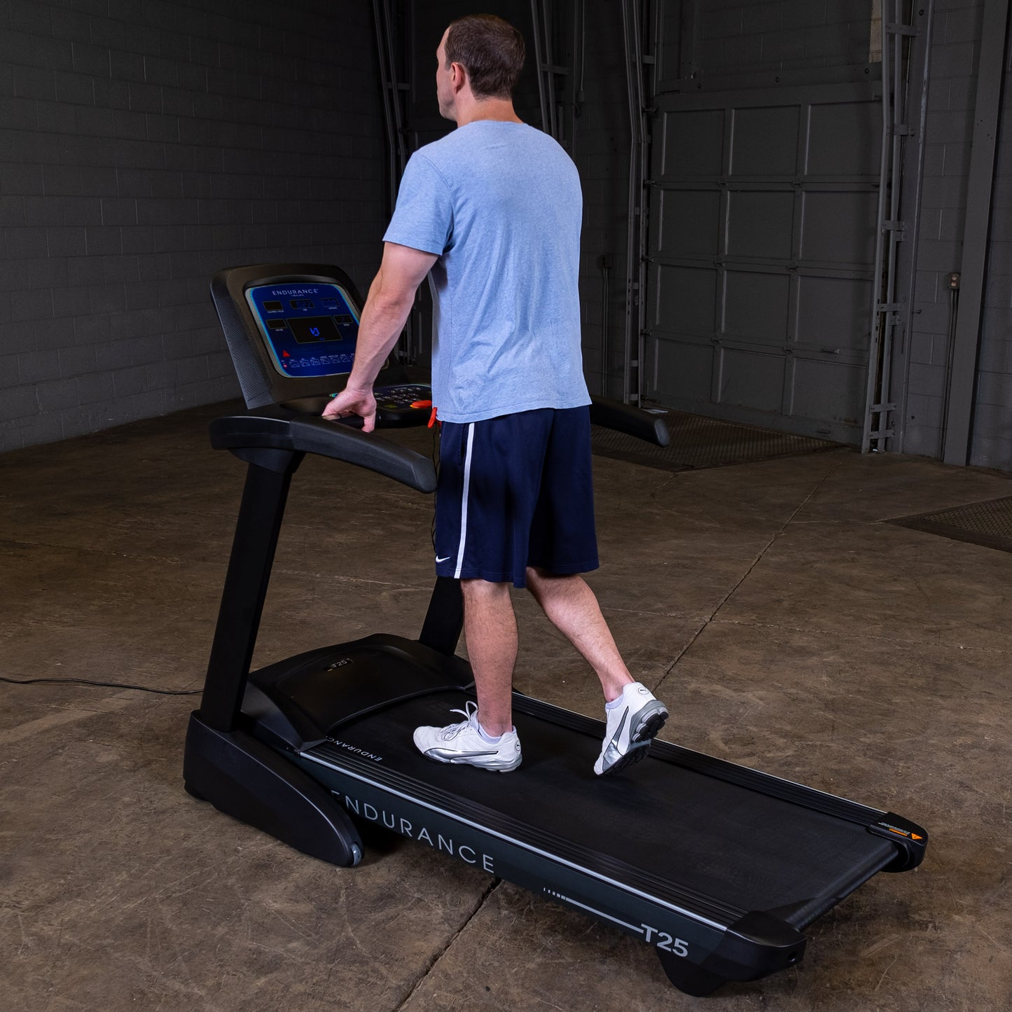 Man walking on the Body-Solid Endurance T25 Folding Treadmill during a home workout.