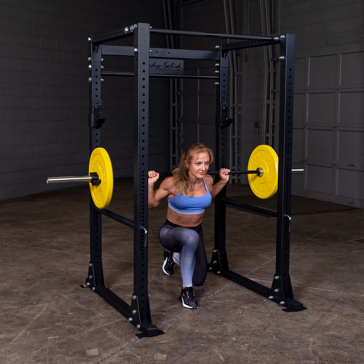 Woman performing squats on the Body‑Solid GPR400 power rack in home gym