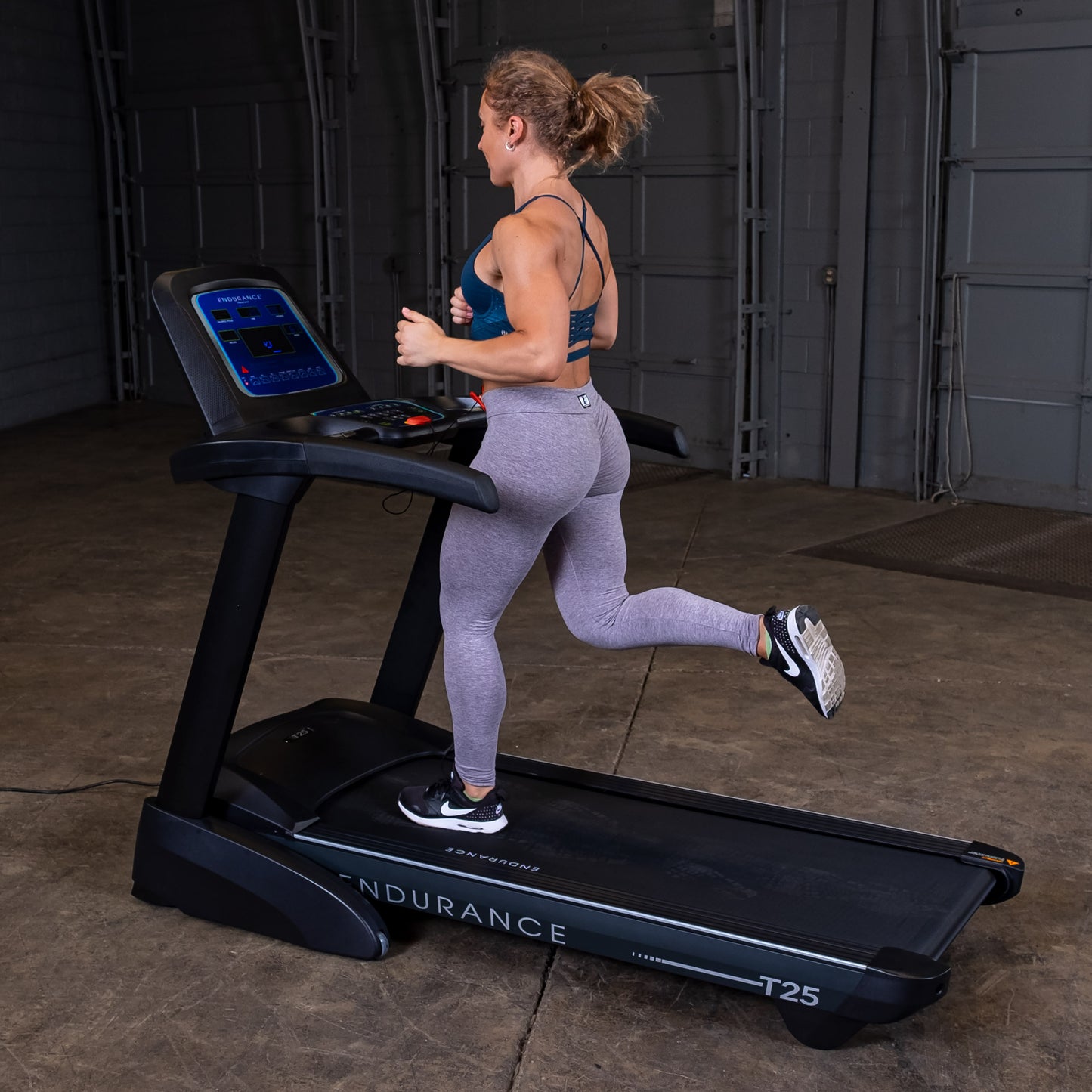 Woman running on the Body-Solid Endurance T25 Folding Treadmill during a home workout.