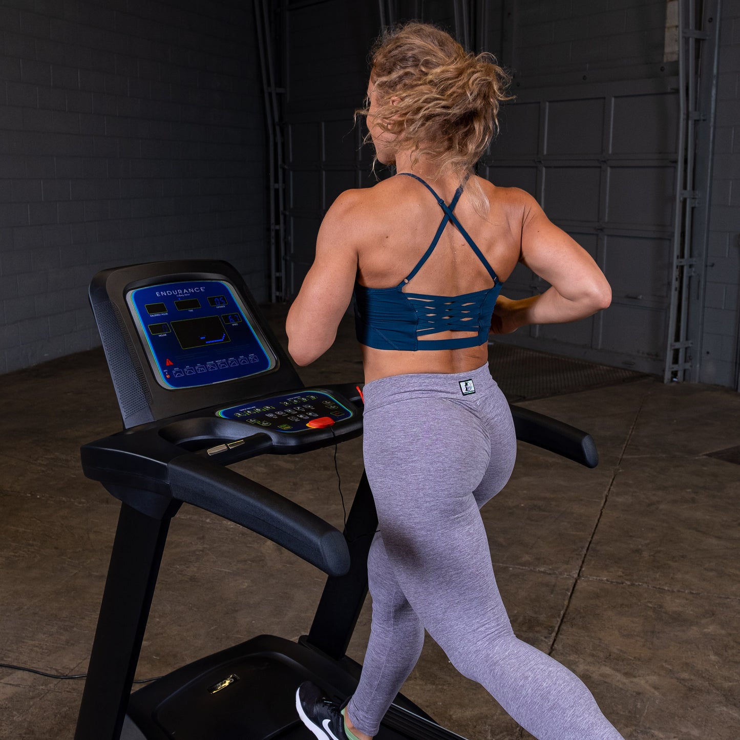 Person jogging on the Body-Solid Endurance T25 Folding Treadmill during a home workout.