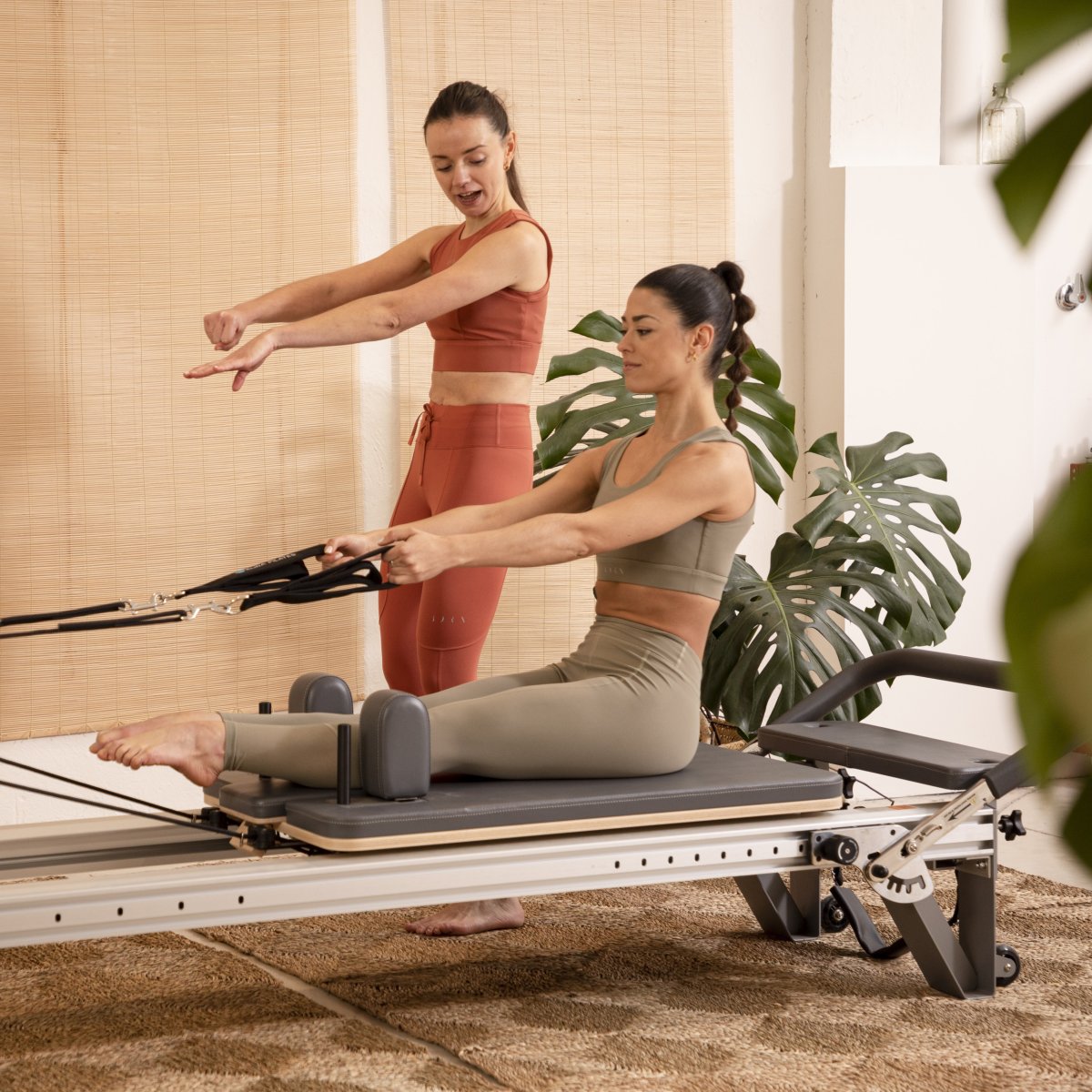 Pilates instructor demonstrating reformer exercises on the Elina Pilates Aluminum Reformer Mentor in black upholstery