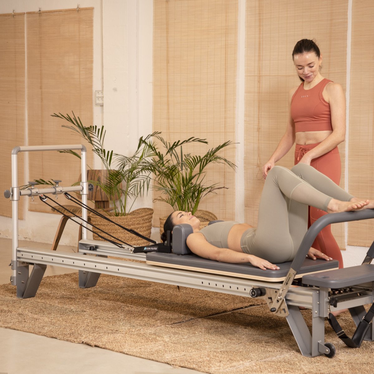 Pilates instructor demonstrating reformer exercises on the Elina Pilates Aluminum Reformer Mentor in black upholstery