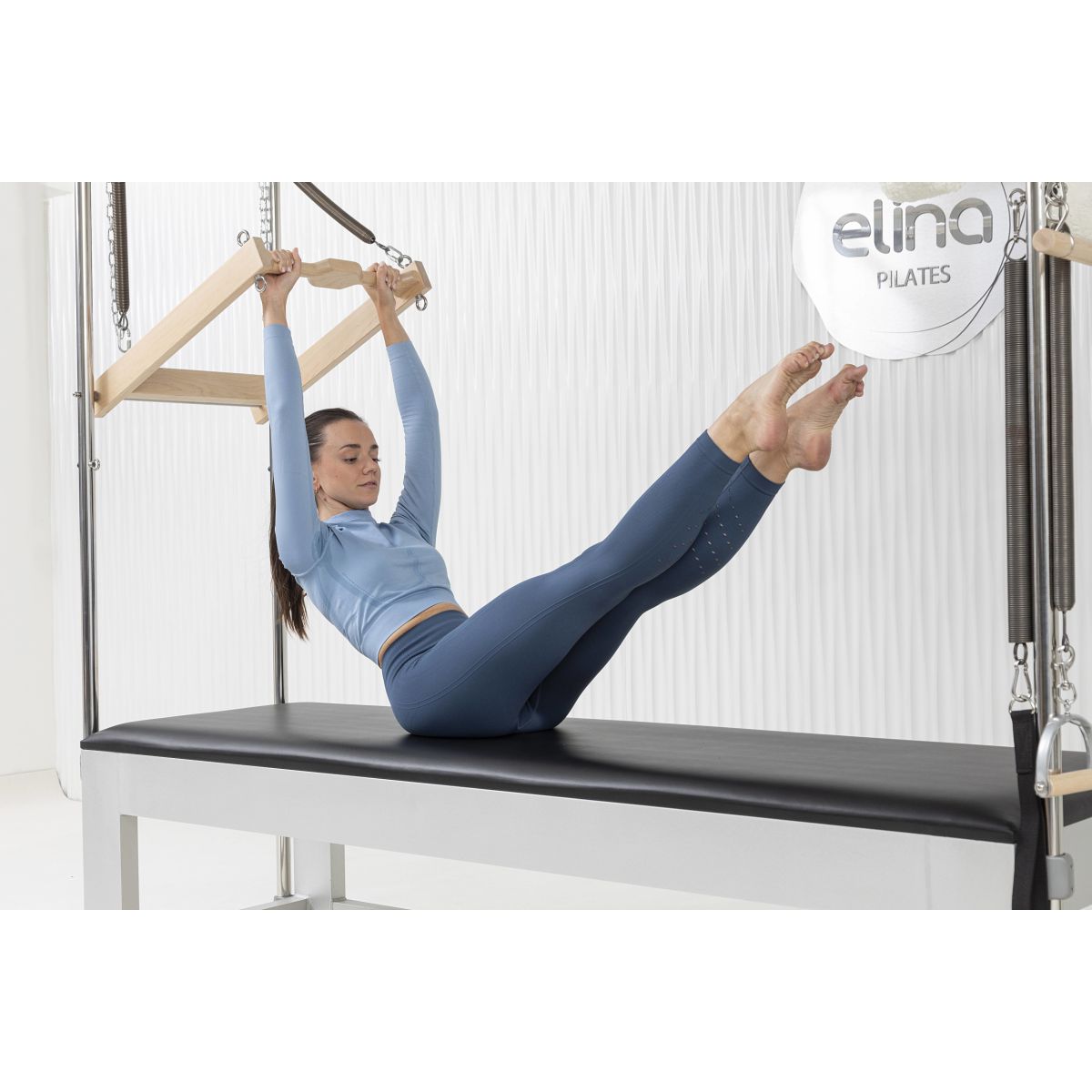Woman doing workout on the Elina Pilates Classic Aluminum Cadillac trapeze