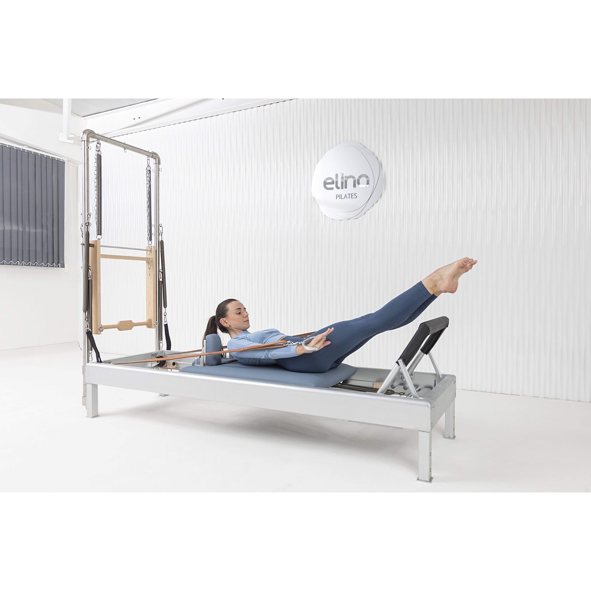 User completing workout on the Elina Pilates Classic Aluminum Reformer 86″ in a studio setting.