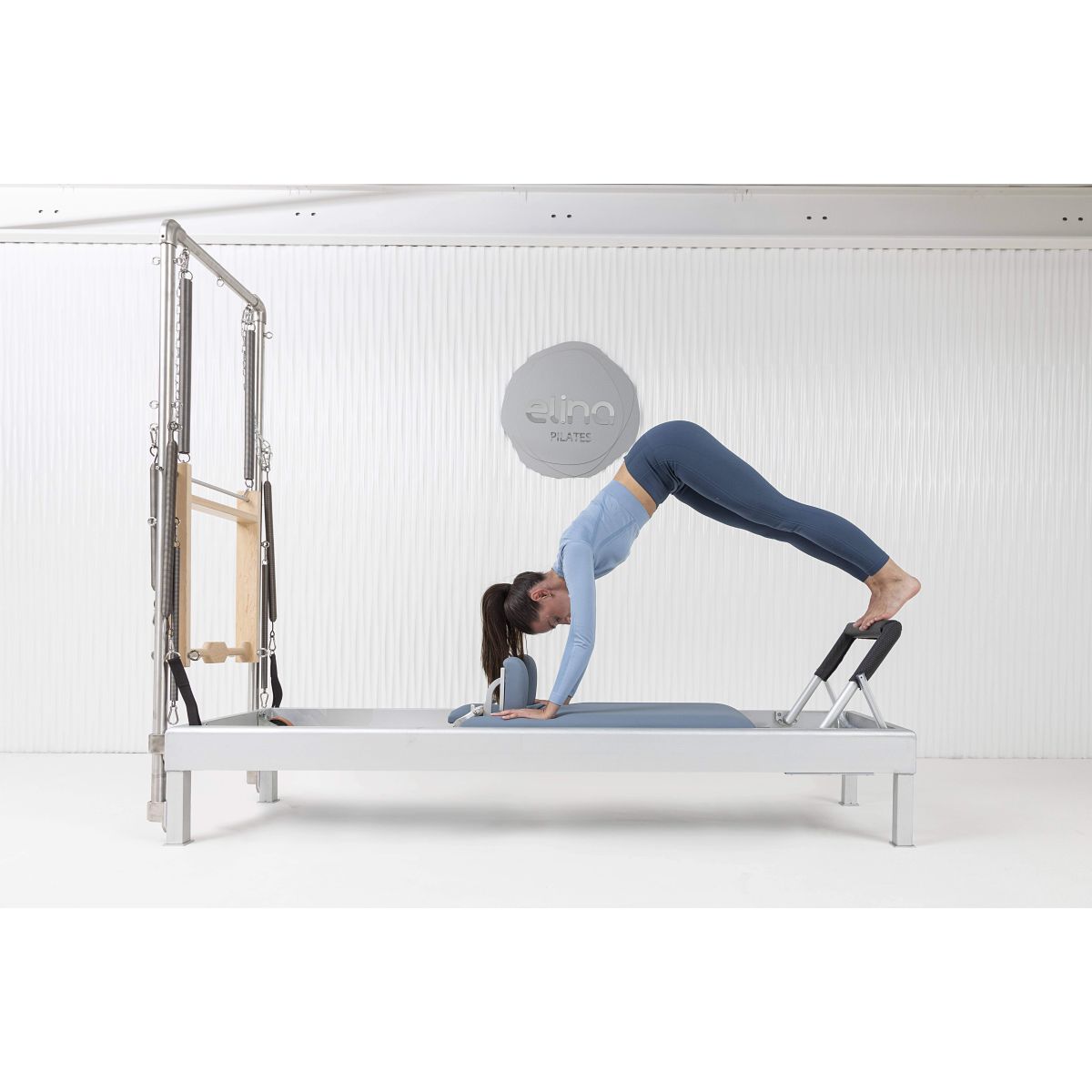 User completing workout on the Elina Pilates Classic Aluminum Reformer 86″ in a studio setting.