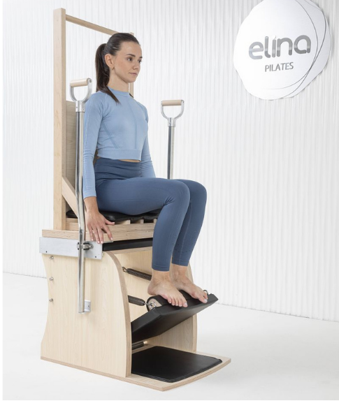 User performing seated Pilates exercises on the Elina Combo Chair with Backrest — demonstrating stability and comfort.