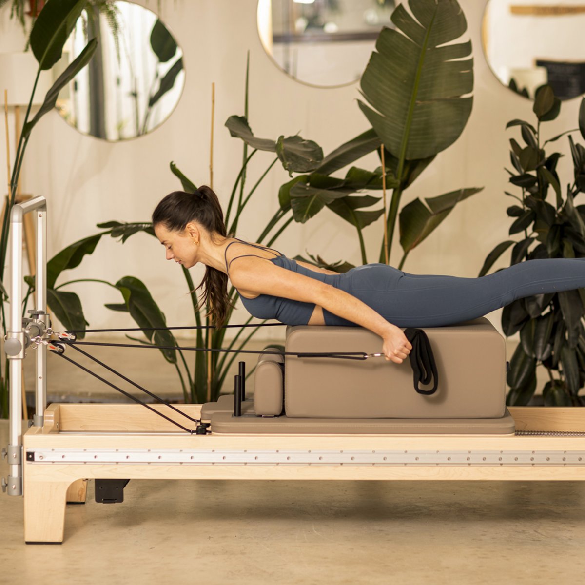 Pilates practitioner performing an exercise on the Elina Pilates Master Instructor™ Reformer with Mini-Tower in studio setting