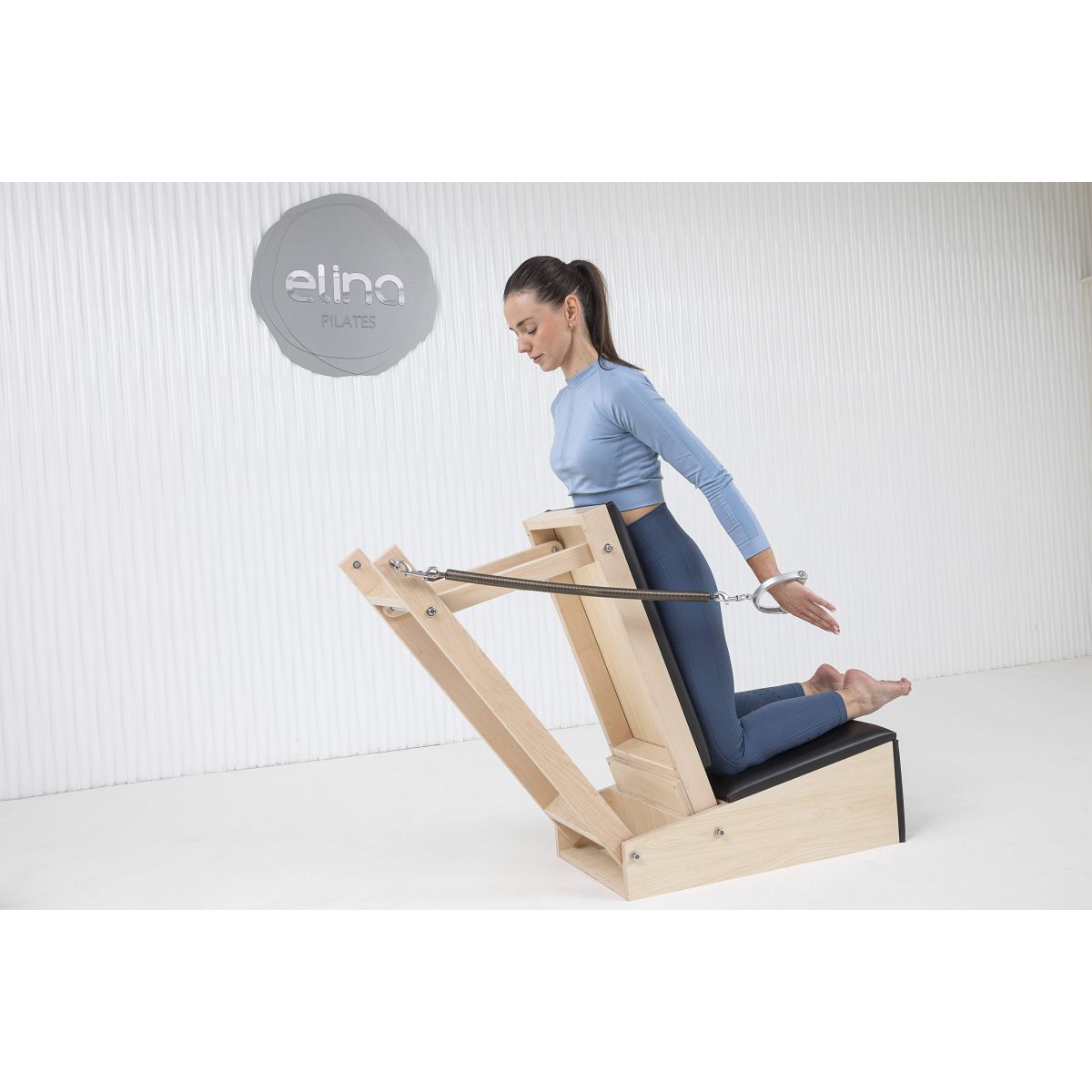 Woman performing pilates workout on the Elina Pilates Baby Chair in Black