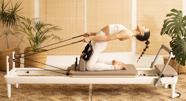 Pilates instructor demonstrating exercises on the Elina Pilates Nubium Reformer in a studio setting