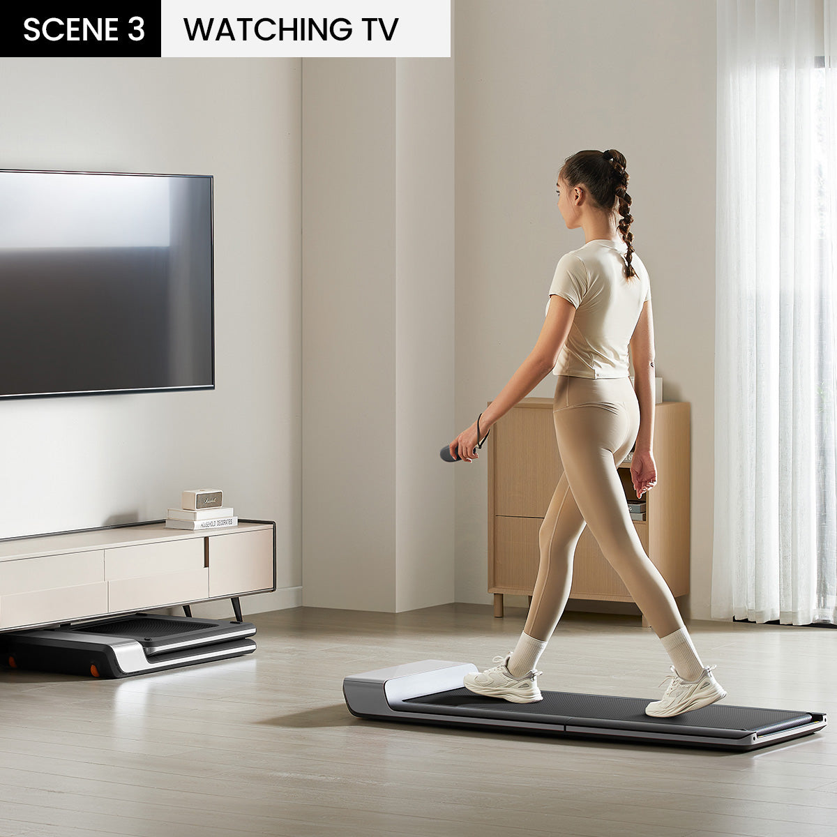 Woman walking on the WalkingPad P1 treadmill under a standing desk setup.