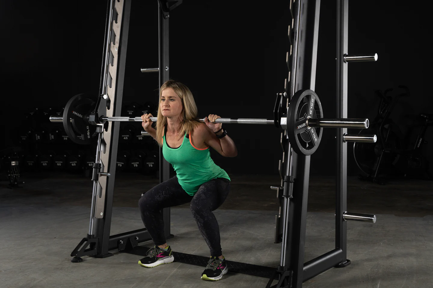 User performing squat on the XMark Commercial Smith Machine with steel frame and guide rods