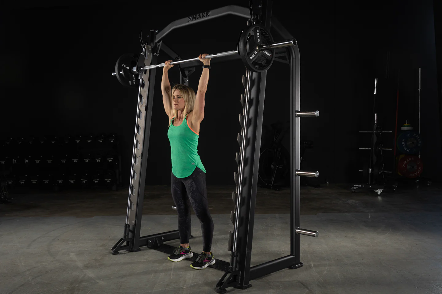 User performing standing overhead press on the XMark Commercial Smith Machine with steel frame and guide rods