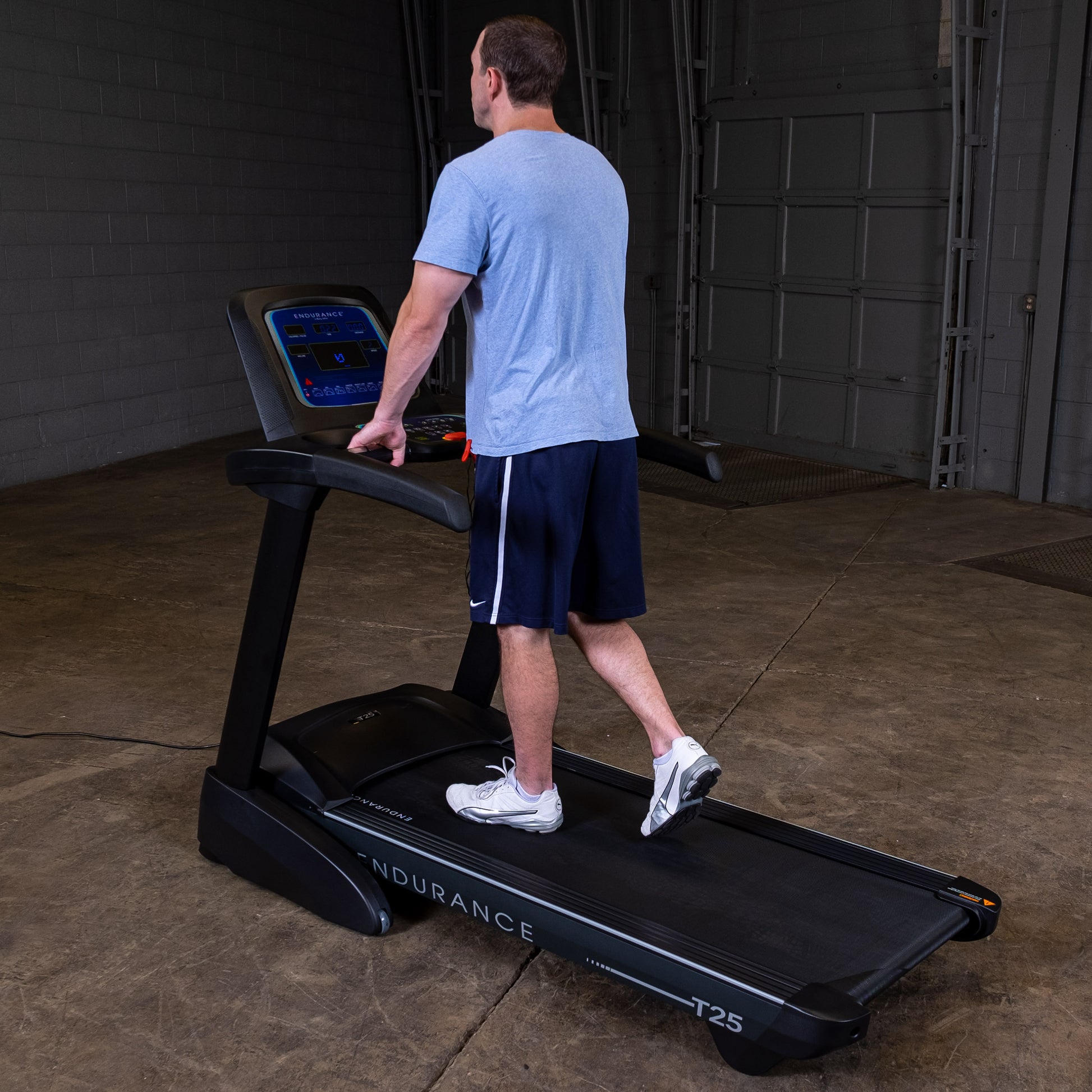 Man walking on the Body-Solid Endurance T25 Folding Treadmill during a home workout.