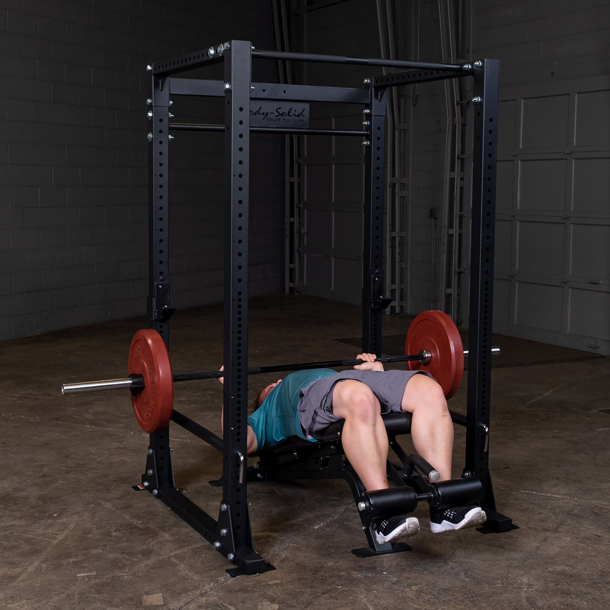 Man performing bench press on the Body‑Solid GPR400 power rack in home gym