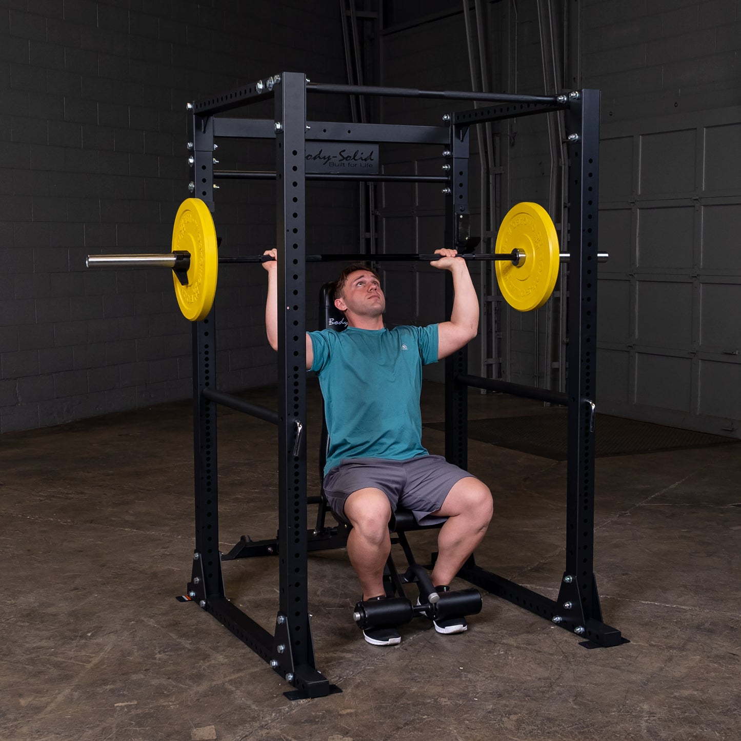 Man performing overhead press on the Body‑Solid GPR400 power rack in home gym