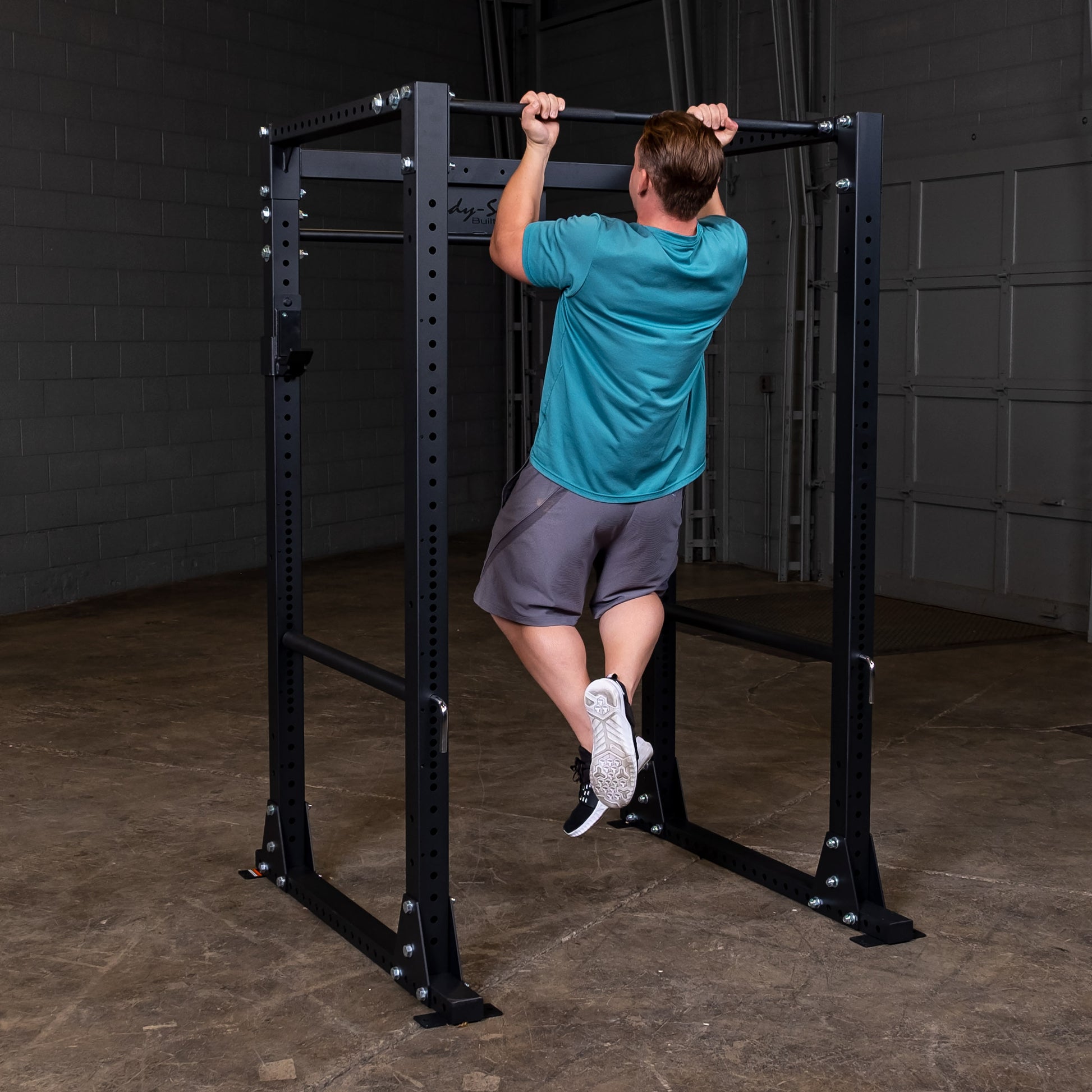 Man performing pullup on the Body‑Solid GPR400 power rack in home gym