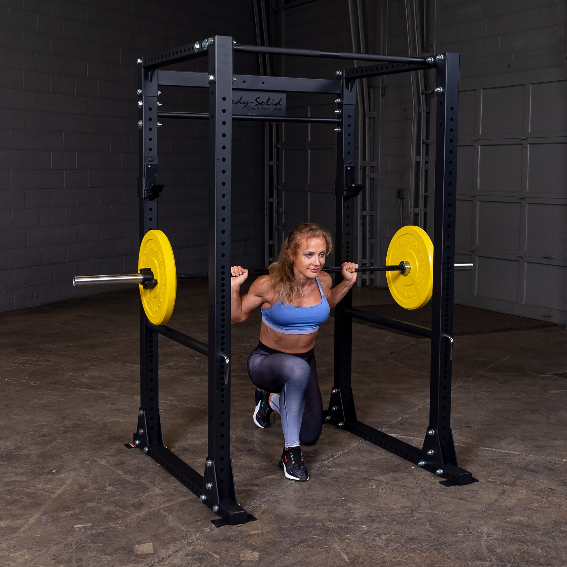 Woman performing squats on the Body‑Solid GPR400 power rack in home gym