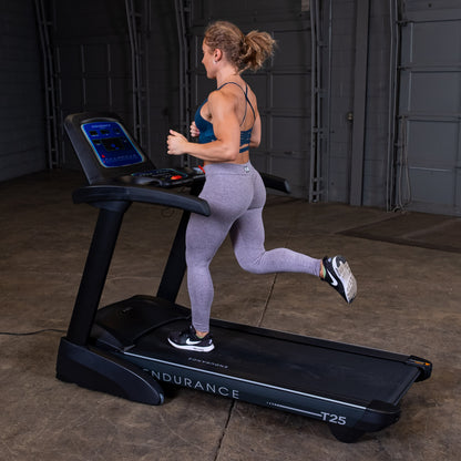 Woman running on the Body-Solid Endurance T25 Folding Treadmill during a home workout.