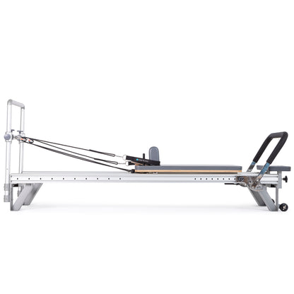 Side view of the Elina Pilates Aluminum Reformer Mentor in grey upholstery with accessories attached