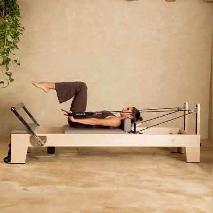 Pilates instructor performing core strengthening exercises on Elina Pilates Elite Wood Reformer with black upholstery