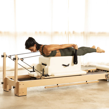 Pilates instructor performing controlled exercises on the Elina Pilates Wooden Reformer Lignum™ with natural beechwood frame