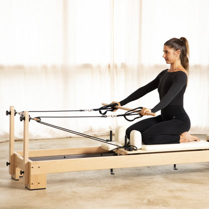 User utilizing the height-adjustable rope pulleys on the Elina Pilates Wooden Reformer Lignum™ for upper-body strength training