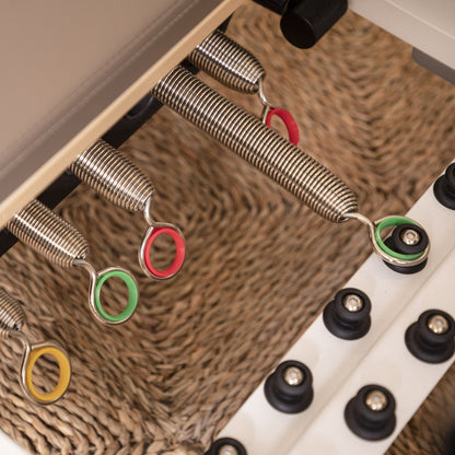 Color-coded alloy springs attached to the Elina Pilates Nubium Reformer showing different resistance levels
