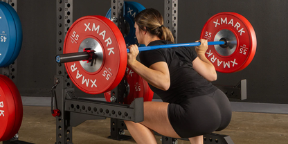Woman performing back squat with XMark Chrome-Plated Color Bumper Plates