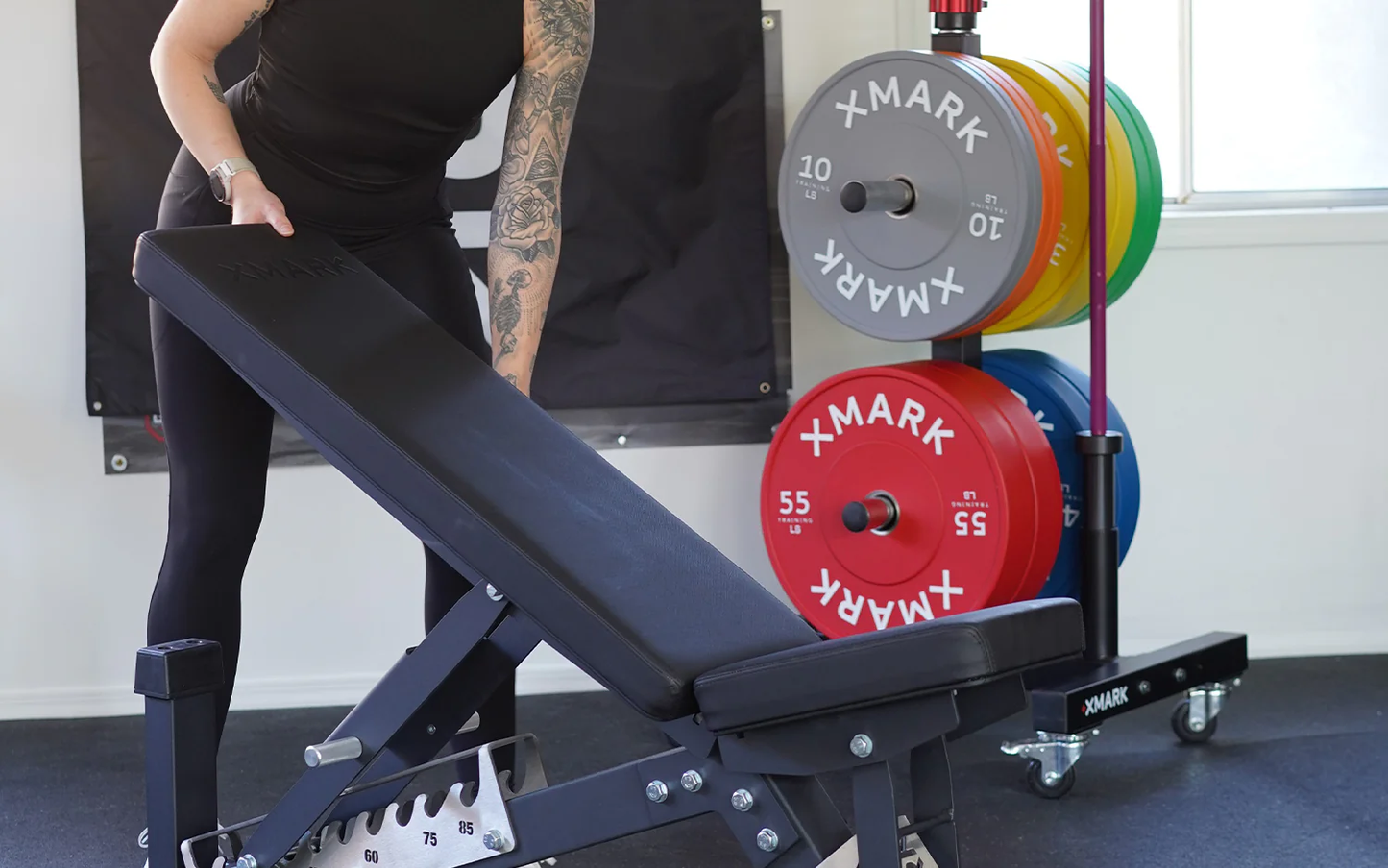 Athlete loading XMark chrome bumper plates onto Olympic bar